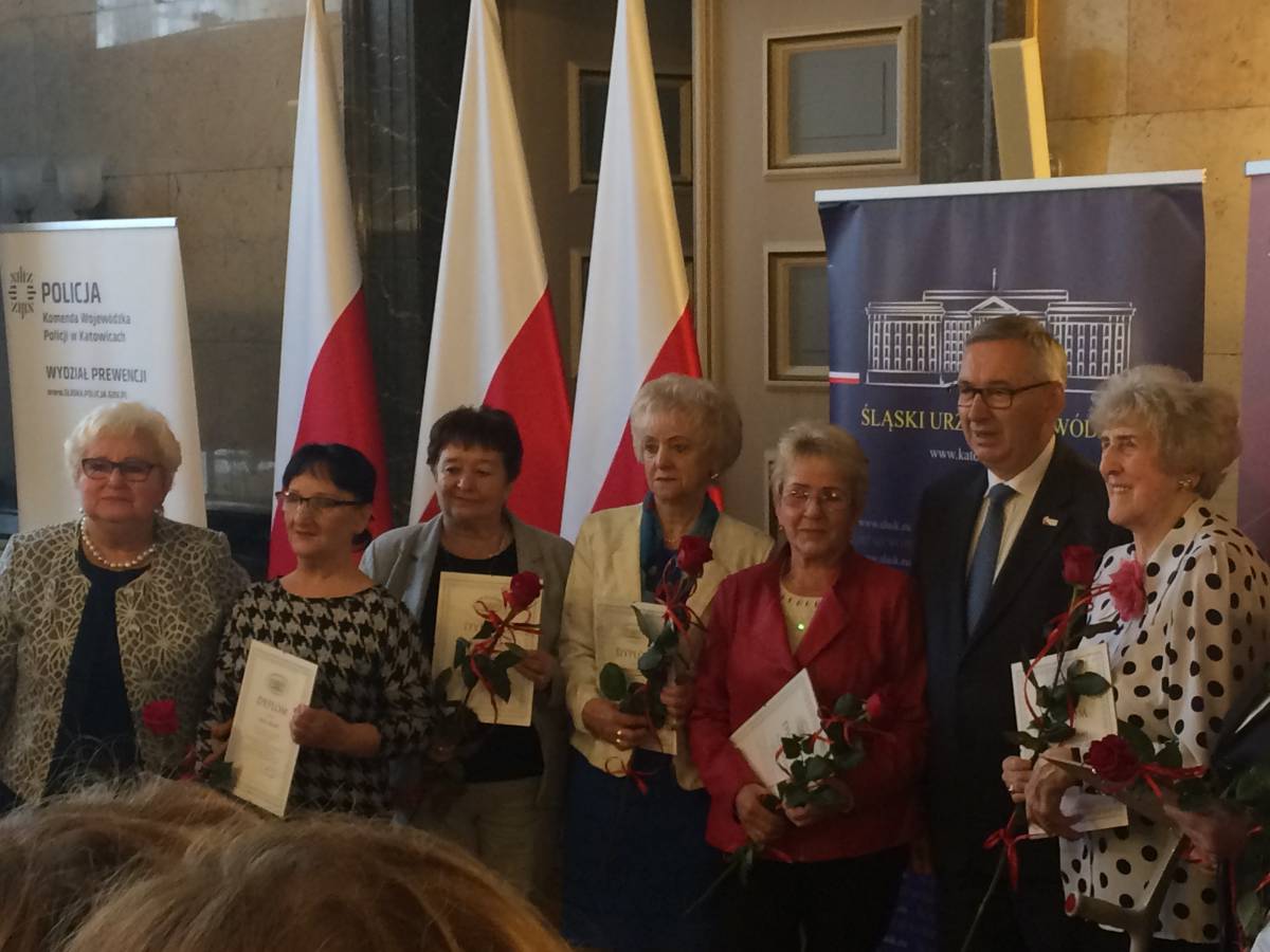 Zdjęcie przedstawiające uhonorowanych dyplomami i czerwonymi różami seniorów.