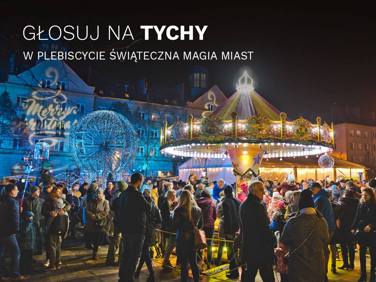 Zdjęcie placu Baczyńskiego w Tychach podczas Jarmarku Bożonarodzeniowego, na zdjęciu oświetlone budynki, karuzela oraz mieszkańcy