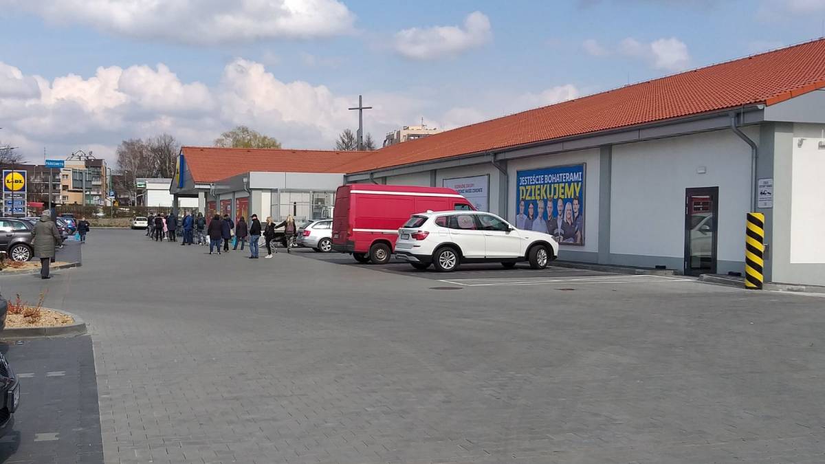 Długa kolejka do sklepu, na zdjęciu osoby w dwumetrowej odległości od siebie