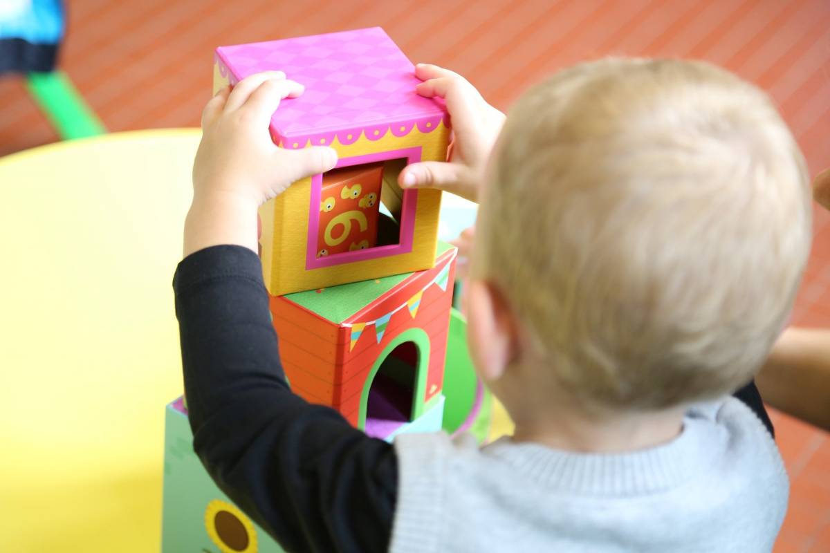 zdjęcie dziecka bawiącego się kartonowymi klockami-kwadratami