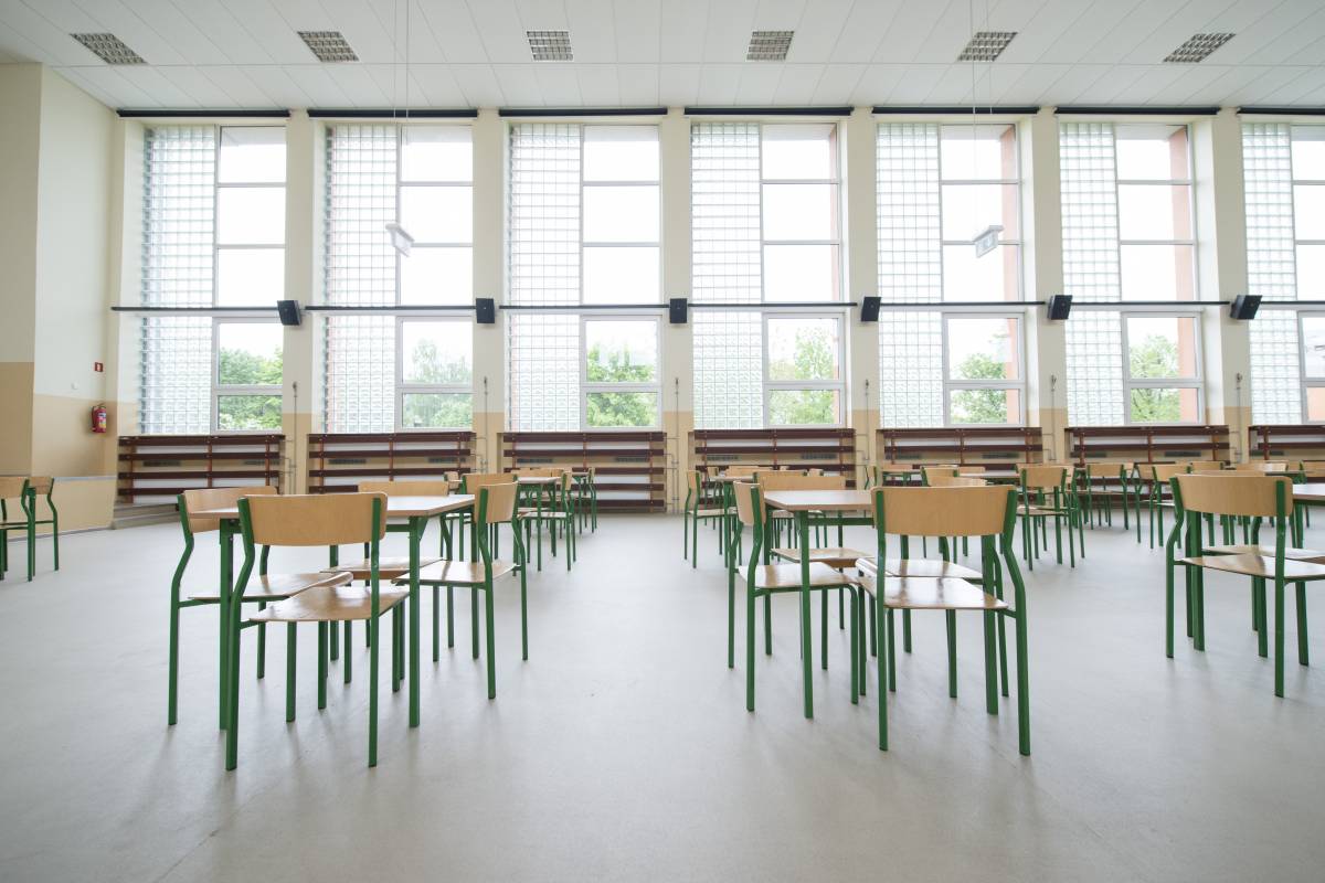 Pusta sala gimnastyczna w szkole z ustawionymi stołami i krzesłami.