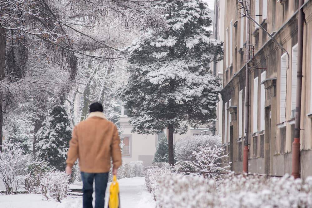 Zima w mieście - zdjęcie przedstawiające zaśnieżony chodnik i sylwetkę mieszkańca. Autor: Michał Janusiński