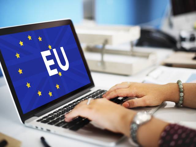 Laptop - na monitorze niebieskie tło z napisem EU i żółtymi gwiazdkami.