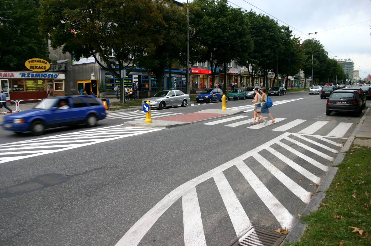 Frgament ulicy Grota-Roweckiego w Tychach. Na zdjęciu dwie kobiety przechodzące przez jezdnie oraz odjeżdżający samochód