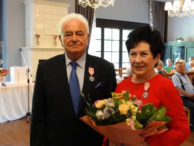 Zdjęcie jubilatów, mężczyzna i kobieta z orderami oraz bukietem kwiatów