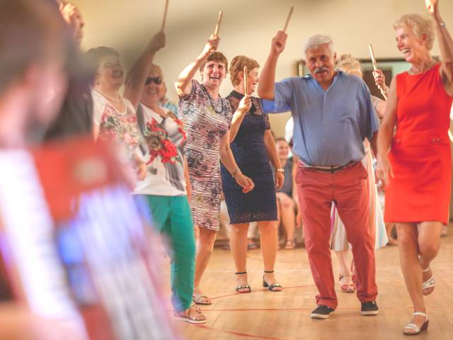 Zdjęcie ukazujące bawiących się i tańczących seniorów podczas potańcówki w Domu Kultury na osiedlu A w Tychach.