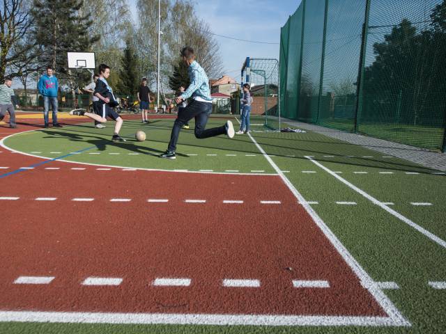 Zdjęcie boiska sportowego w Tychach - w tle biegający chłopcy z piłką