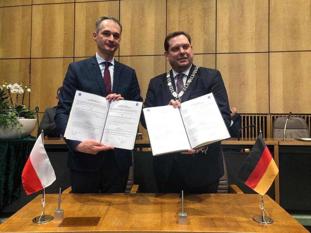 Zdjęcie Macieja Gramatyki, zastępcy prezydenta Miasta Tychy z Danielem Schrantzem, burmistrzem Oberhausen. Obaj trzymają w rękach podpisane umowy o partnerstwie i pozują z nimi do zdjęcia.