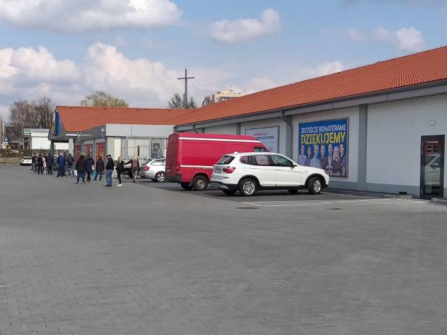 Długa kolejka do sklepu, na zdjęciu osoby w dwumetrowej odległości od siebie