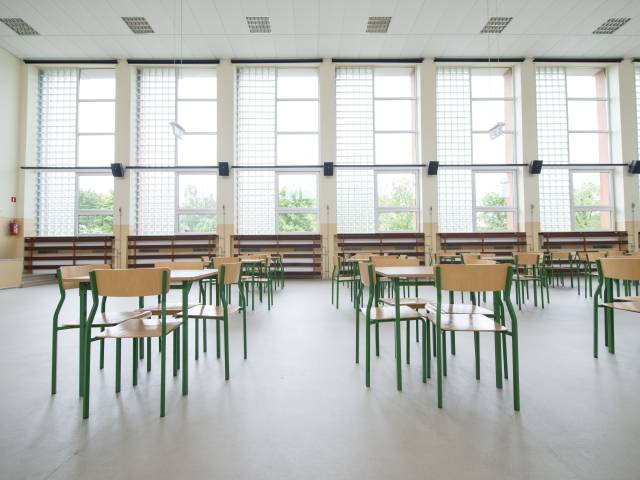 Pusta sala gimnastyczna w szkole z ustawionymi stołami i krzesłami.