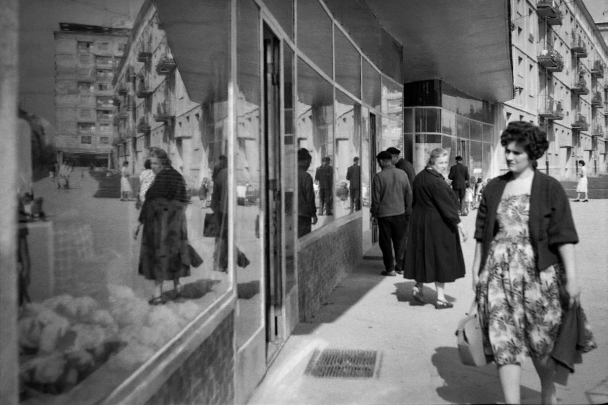 Zdjęcie przestawające kobietę przechodzącą obok wystawy sklepowej. Fotografia czarno-biała z archiwum Muzeum Miejskie w Tychach, z roku 1962. Autor: Zygmunt Kubski