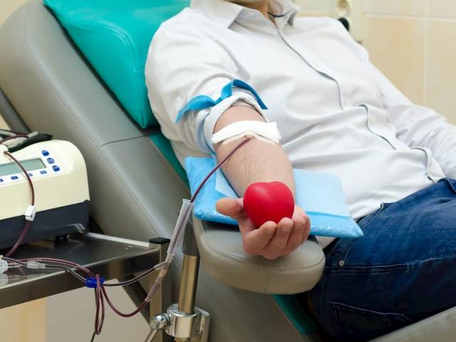 Zdjęcie przedstawiające postać oddającą krew, trzymającą  w dłoni czerwone gumowe serce