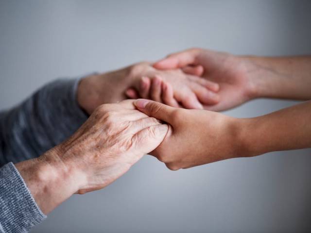 Zdjęcie - dłonie młode człowieka trzymające dłonie starszej osoby.