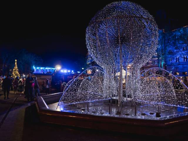 Zdjęcie podświetlonej fontanny w zimowej scenerii Placu Baczyńskiego.