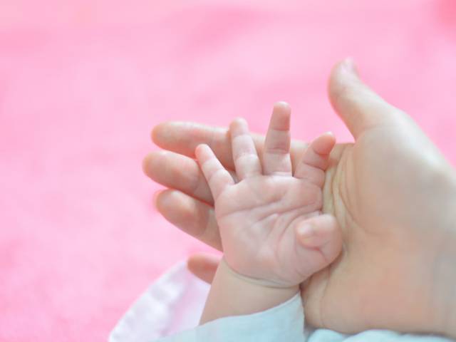 Dłoń niemowlaka w na dłoni kobiety. 