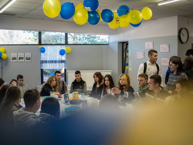Młodzież w sali udekorowanej balonami w barwach Ukrainy.