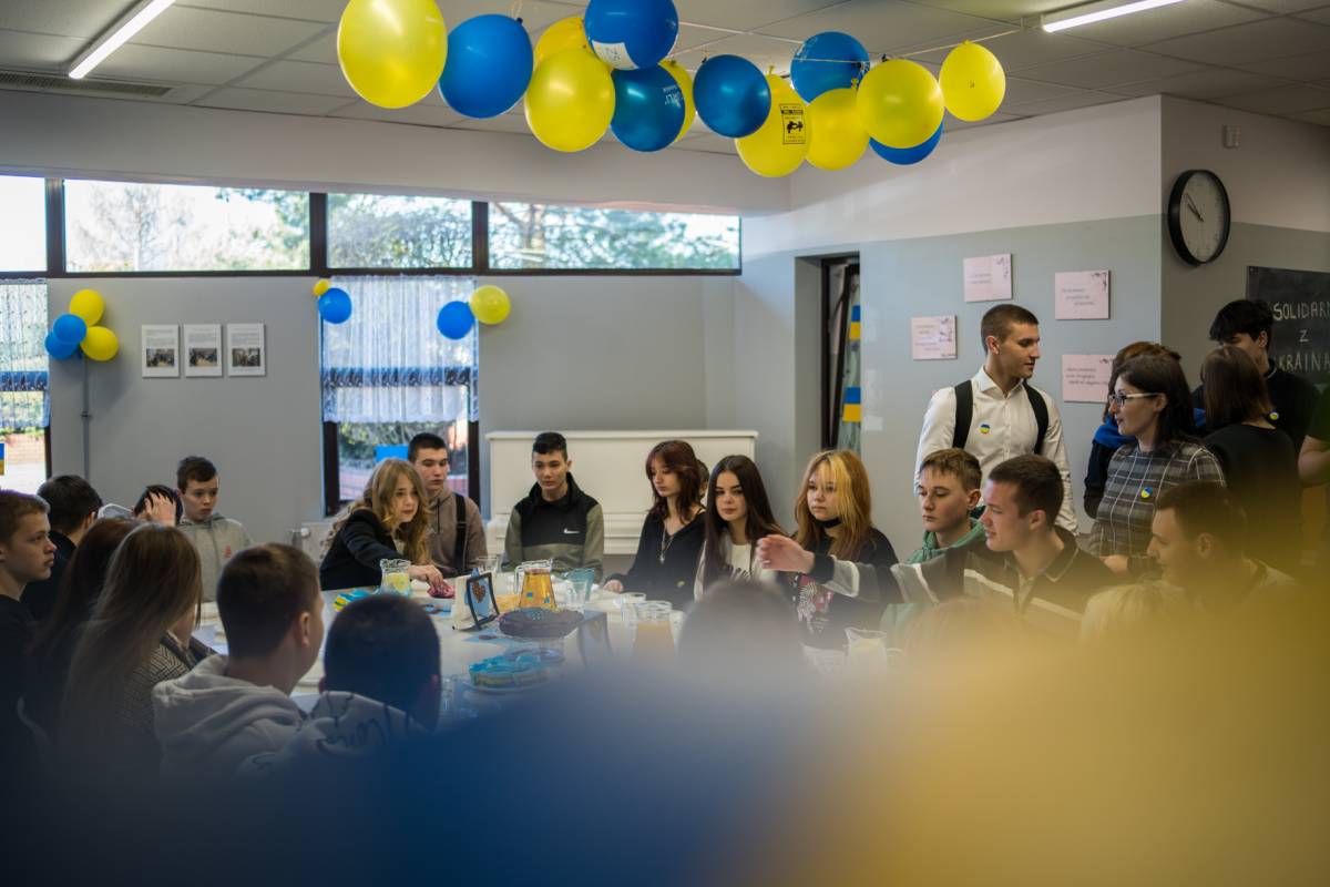 Młodzież w sali udekorowanej balonami w barwach Ukrainy.