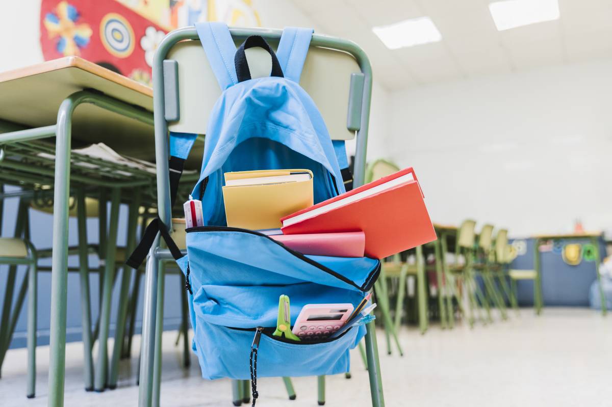 Plecak szkolny powieszony na krześle z książkami i zeszytami
