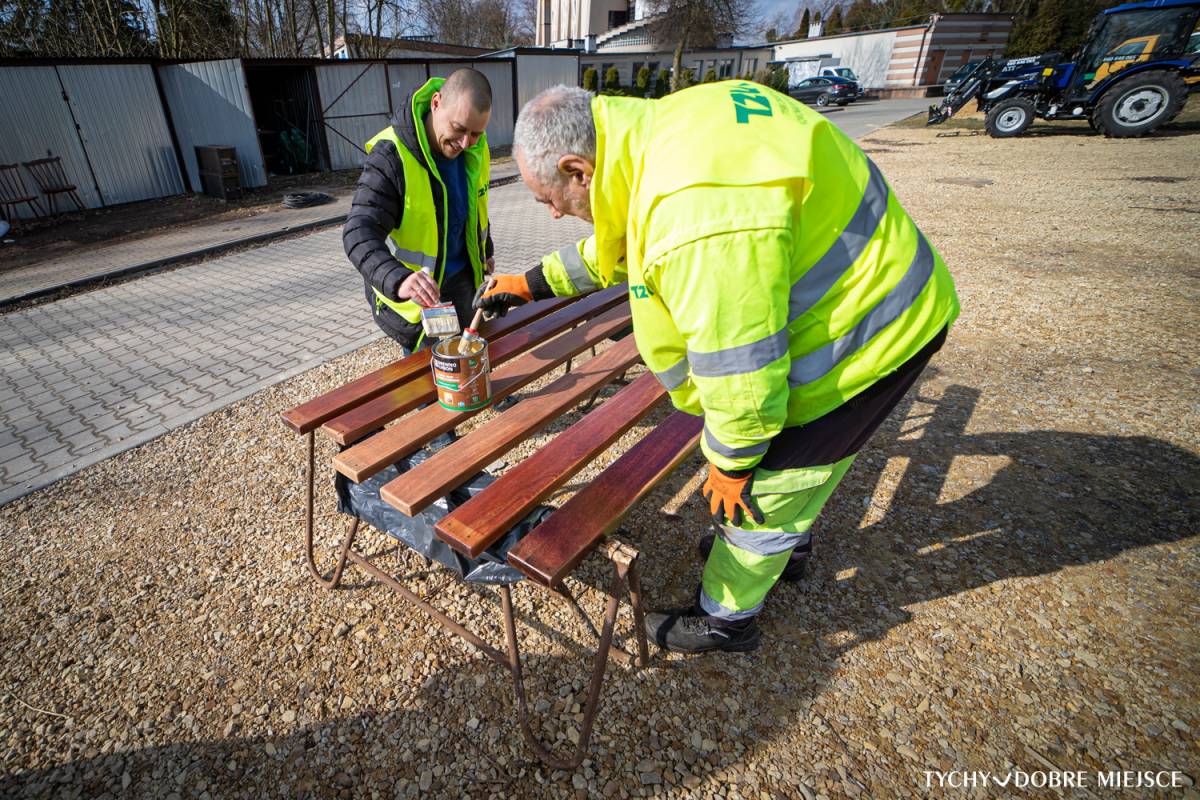 Dwóch pracowników TZUK odmalowuje ławki z tyskich parków