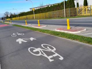Droga rowerowa i ścieżka dla pieszych, obok ulica i trwanik.