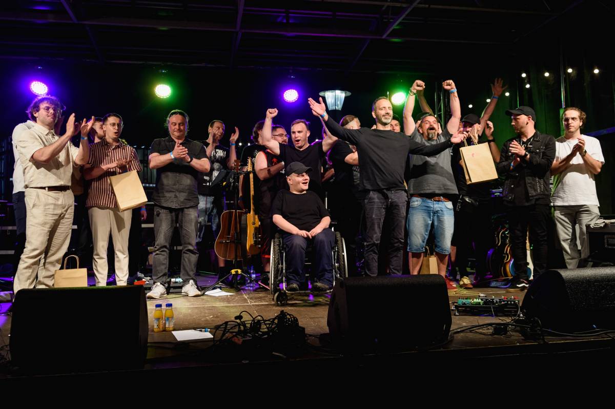 Grupa ludzi, która zwyciężyła w konkursie stoi na scenie z nagrodami.