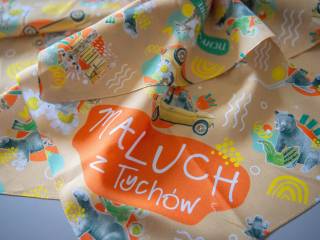 Pomarańczowa chusta z kolorowymi symbolami miasta i napisem "Maluch z Tychów".